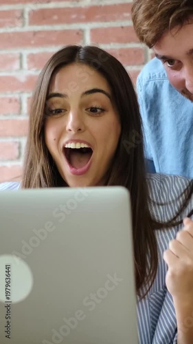 Joyful Young Adults Collaborating and Reacting to Content on a Laptop