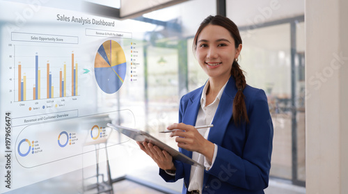 Professional Asian businesswoman using digital tablet to analyzing sales growth and financial data dashboard on virtual screen in modern office.