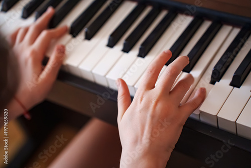 Hands playing piano keys in a bright room