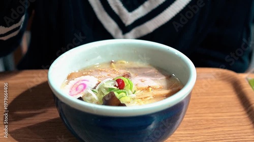 Young tourist woman eating Creamy Tonkotsu Ramen with Toppings in a Bowl (Japanese Noodle Soup)
