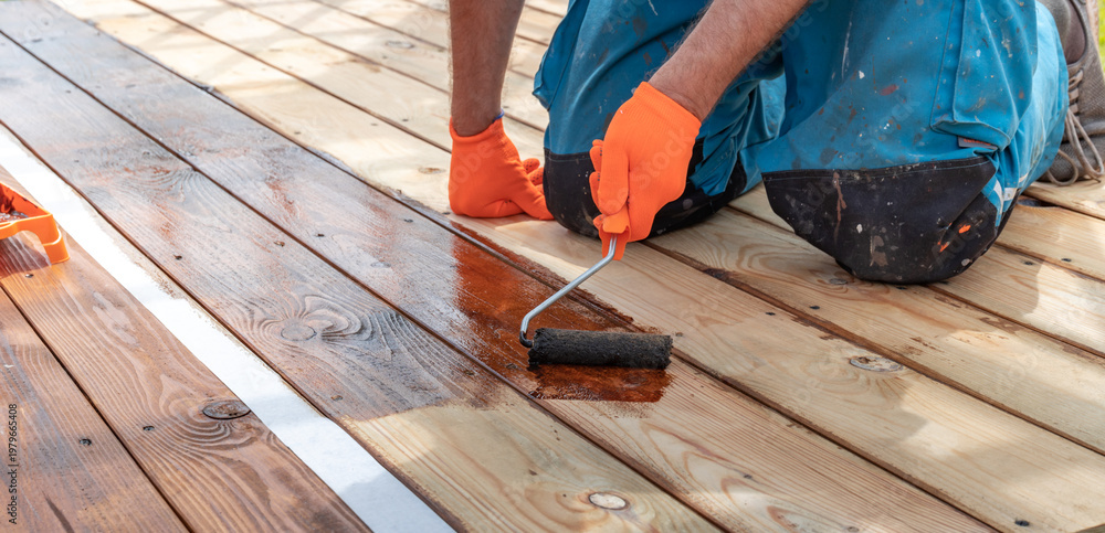 custom made wallpaper toronto digitalWorker applies wood stain with roller on deck surface