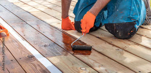Wallpaper Mural Worker applies wood stain with roller on deck surface Torontodigital.ca