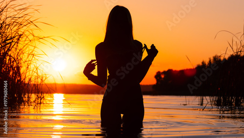 Girl silhouette in the lake during beautiful sunset