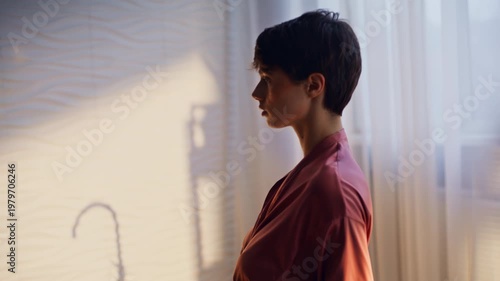 Brunette taking off silk robe standing naked back closeup. Woman spa procedures