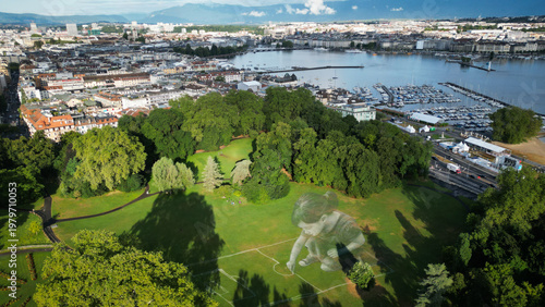 Aerial view of verdant parkland meets the shimmering waters of Lake Geneva, nestled against a backdrop of urban architecture, Geneve, Geneve, Switzerland.