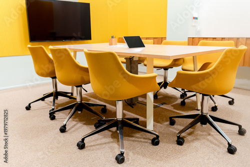 A modern conference room with a long table surrounded by yellow upholstered office chairs with a professional atmosphere.