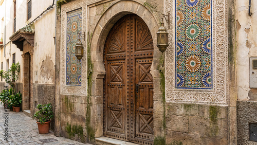 Ornate Cedar Wood Doorway Beneath Horseshoe Arch With Mosaic Panels, Chiseled Stucco And Metal Lanterns, Historic Quarter Heritage Architecture Detail