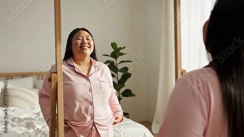Woman smiling at mirror reflection indoors representing self confidence self love and positive body image lifestyle
