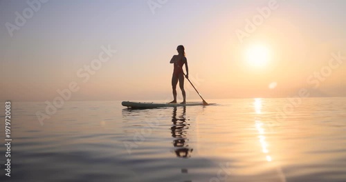 Young woman walking on sup board by the sea during summer vacation