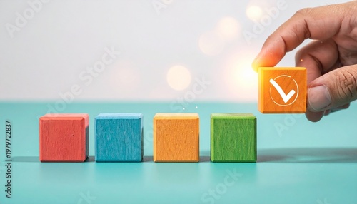 Hand holding checkmark block above colorful arranged wooden blocks