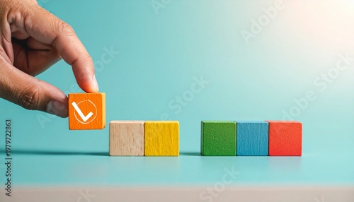 Hand holding checkmark block above colorful arranged wooden blocks