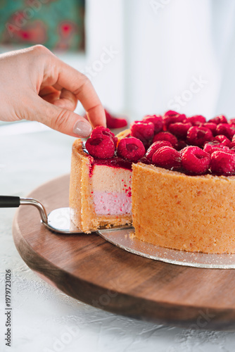 Hand Taking Slice Of Raspberry Cake From Board