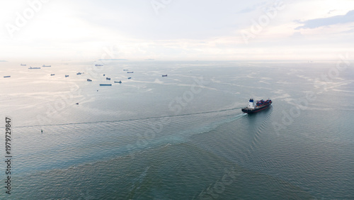 Obraz na płótnie Commercial Container Ship Navigating Across Open Ocean Waters Past Anchored Carg