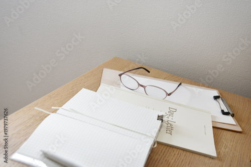Notebook glasses and clipboard on wooden desk in minimal office