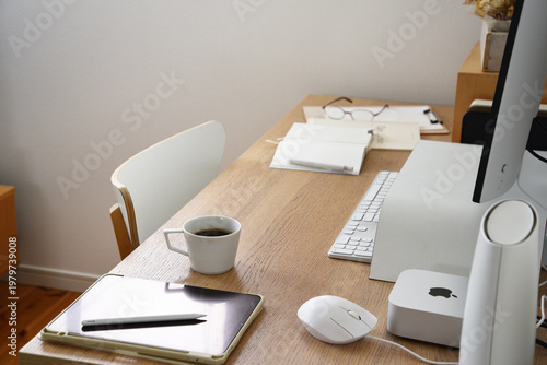 Minimal home office desk with coffee cup computer and notebook