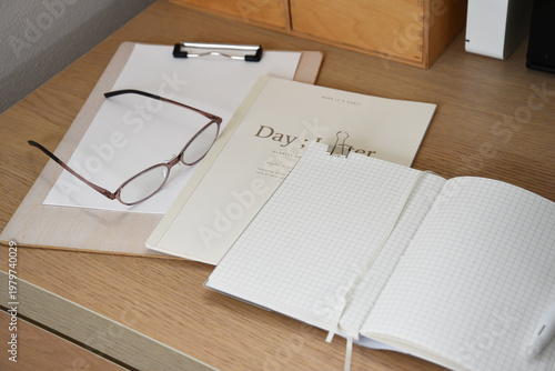 Notebook glasses and clipboard on tidy wooden office desk