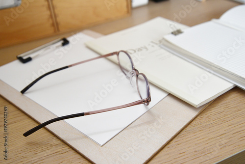 Eyeglasses on clipboard and notebook close up desk stationery