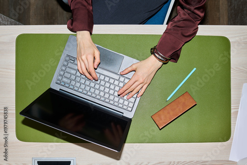 Фотография Overhead shot of young woman typing on laptop at desk, managing online work and digital communication