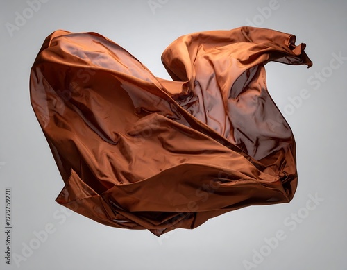 Flowing, bronze fabric mid-air. Silky material caught in motion, forming elegant swirls against a gray backdrop
