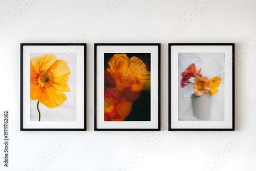 Three framed floral photographs on a white wall: a yellow flower, a blurred orange bloom, and flowers in a white vase. Minimalist interior wall decor composition.