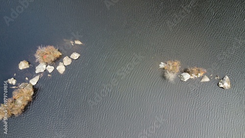 Aerial view of isolated rocks in a lake 