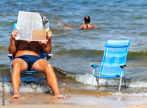 Foto A man is relaxing in an armchair right by the waves, engrossed in his reading an