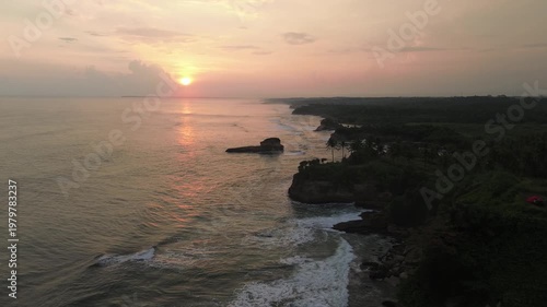 Dramatic Sunset Seascape with Waves Hitting Rocky Coast and Palm Tree Silhouettes
