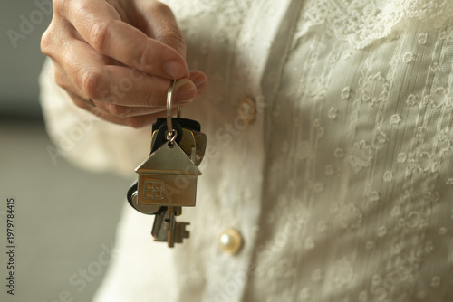 Woman holds keys to new house or apartment. Moving to new apartment, buying or renting real estate