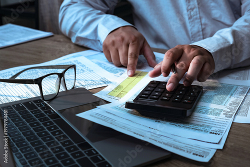 Fotografía Business professional calculating financial data with calculator and laptop, analyzing documents, budgeting expenses, tax planning, accounting and finance concept in modern office workspace