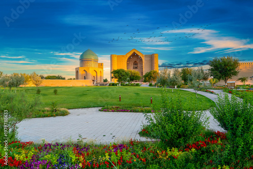 Turkestan, Kazakhstan - June 03, 2025: Scenic early morning sunrise view of the historical Mausoleum of Khoja Ahmed Yasawi (Қожа Ахмет Ясауи) surrounded by spring flowers