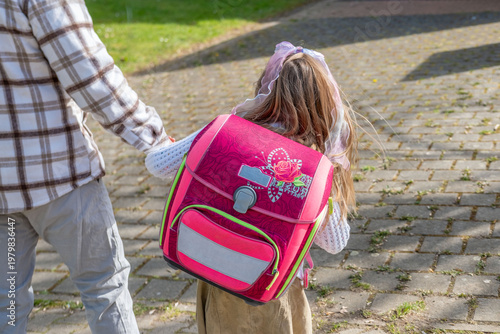 Fotografie senior man leading young schoolgirl with backpack by hand, potential stranger da