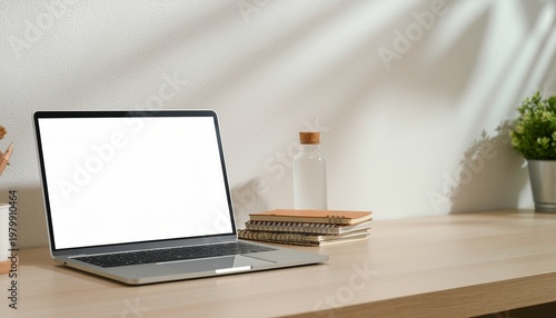 Soft beige workspace with open laptop books and small potted plant