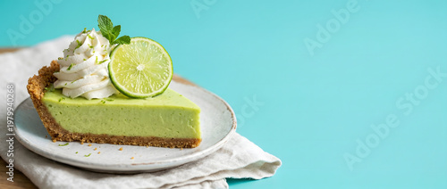 Key Lime Pie with whipped cream and lime slice, isolated against turuoise background, copy space