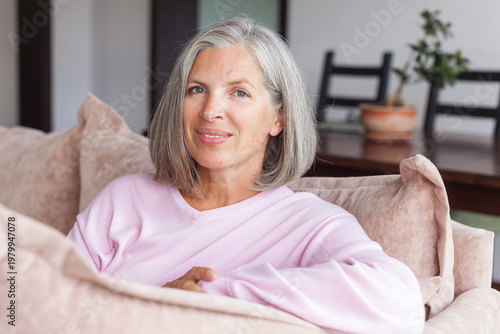 Portrait happy healthy middle aged woman sitting on comfortable couch at home