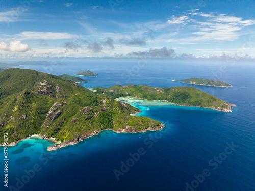 Vast green mountains and turquoise bay stretch out under a bright blue sky with clear waters. Seychelles, Mahe.