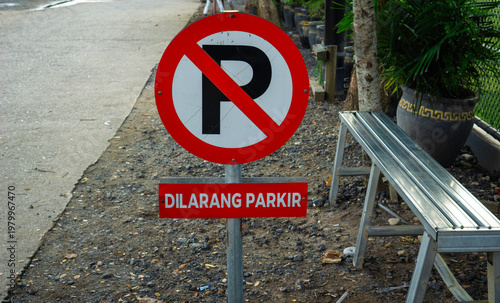 Red no parking sign on roadside in front of mini soccer field