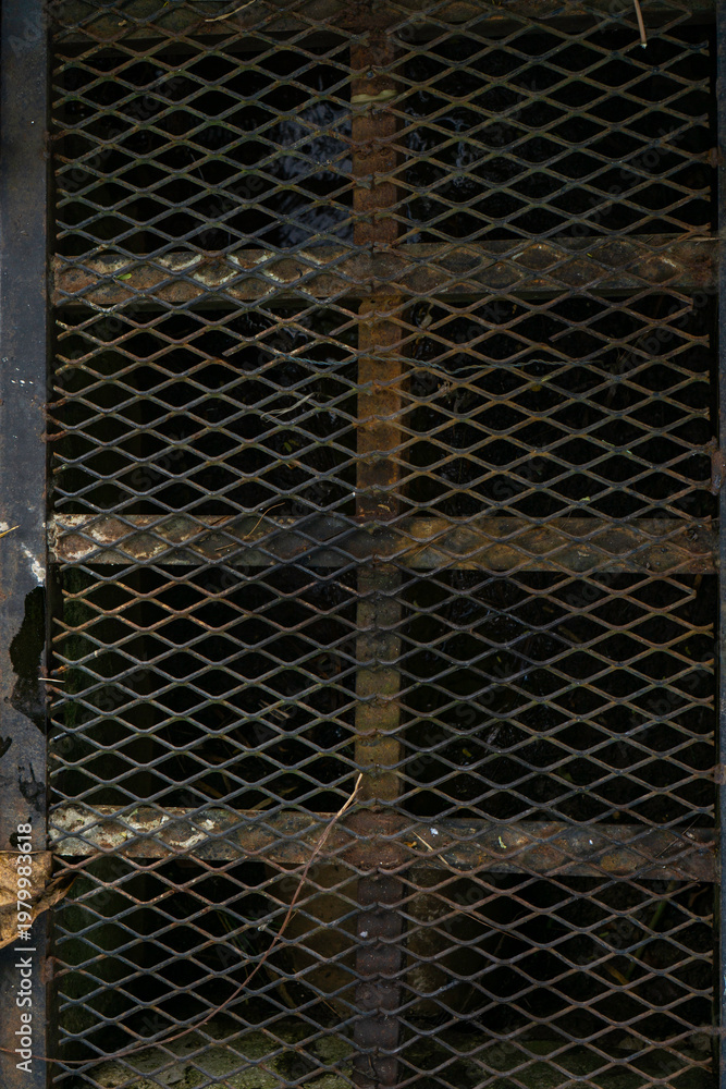 Fototapeta premium Rusted black iron drain cover outdoors with weathered metal texture