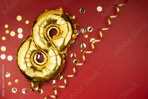 8th birthday celebration. Gold festive balloons number 8 year anniversary on red background with confetti. Birthday or wedding event.