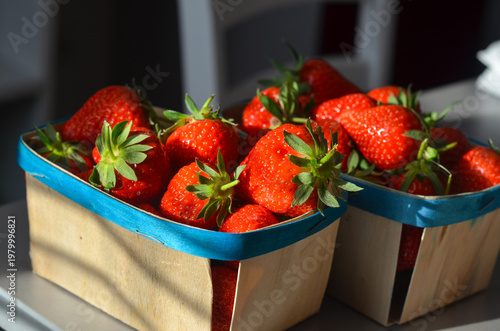 фотографія Two wooden baskets filled with ripe red strawberries on a kitchen counter