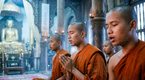 Group of buddhist monks praying and meditating during traditional religious ceremony in temple