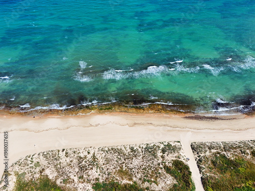 Aerial shot sandy beach along vibrant turquoise Mediterranean Sea, top view. Coastal landscape, travel destination, vacation and tourism concept. Torre de la Horadada, Costa Blanca, Alicante, Spain