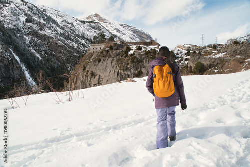 A girl hiking along a snow-covered trail in a mountainous landscape. In the Pyrenees in Spain.