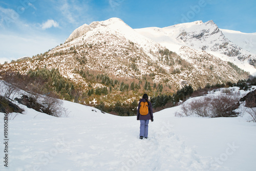 A girl hiking along a snow-covered trail in a mountainous landscape. In the Pyrenees in Spain.