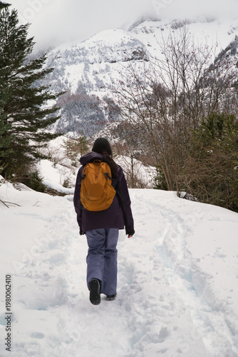 A girl hiking along a snow-covered trail in a mountainous landscape. In the Pyrenees in Spain.