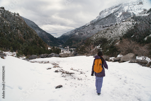 A girl hiking along a snow-covered trail in a mountainous landscape. In the Pyrenees in Spain.