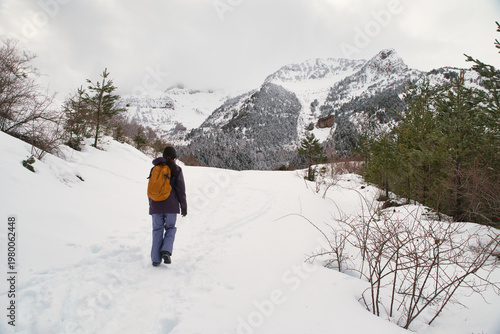 A girl hiking along a snow-covered trail in a mountainous landscape. In the Pyrenees in Spain.