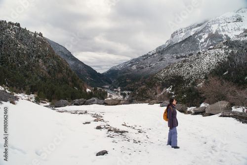 A girl hiking along a snow-covered trail in a mountainous landscape. In the Pyrenees in Spain.