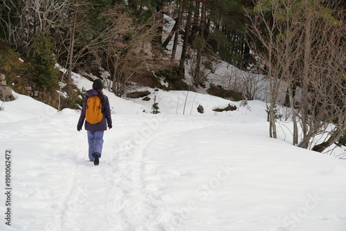 A girl hiking along a snow-covered trail in a mountainous landscape. In the Pyrenees in Spain.