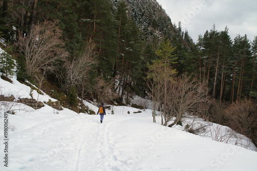 A girl hiking along a snow-covered trail in a mountainous landscape. In the Pyrenees in Spain.
