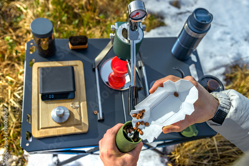 Manual portable espresso maker brewing coffee beans outdoors in mountains camping setup